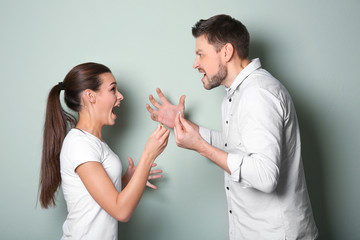 Young couple arguing on color background