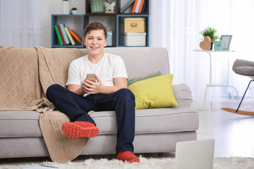 Fototapeta premium Teenage boy with smartphone at home