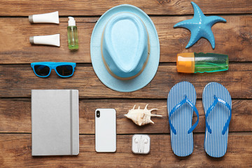Flat lay composition with smartphone and beach objects on wooden background