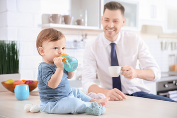 Morning of cute baby boy and his dad in kitchen