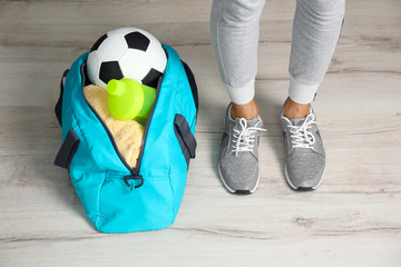 Young man in sportswear and bag with gym equipment indoors
