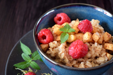 Porridge with apples, raspberries and honey topped with mint. Healthy breakfast meal