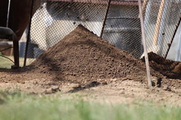 A sifting of earth through sieve. Iron shovel, iron barrel, small iron circle. Through grass on...