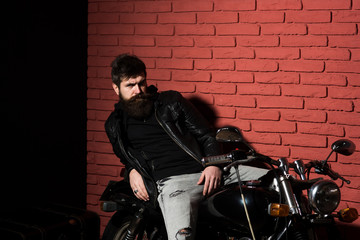 Fototapeta na wymiar bearded biker. bearded biker sitting on motorbikie. bearded biker in leather jacket. bearded biker in repair shop, copy space. this bike will be perfect.