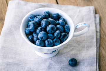 blueberry in a white vintage cup on a wooden table