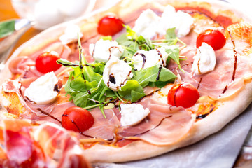 close up of delicious italian pizza with ham, mozzarella and tomatoes