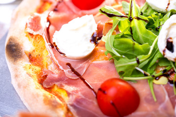 close up of delicious italian pizza with ham, mozzarella and tomatoes