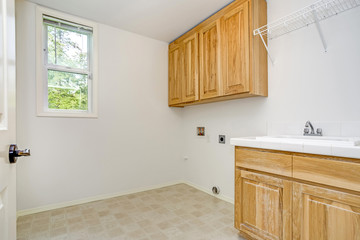 White laundry room with wooden cabinets.