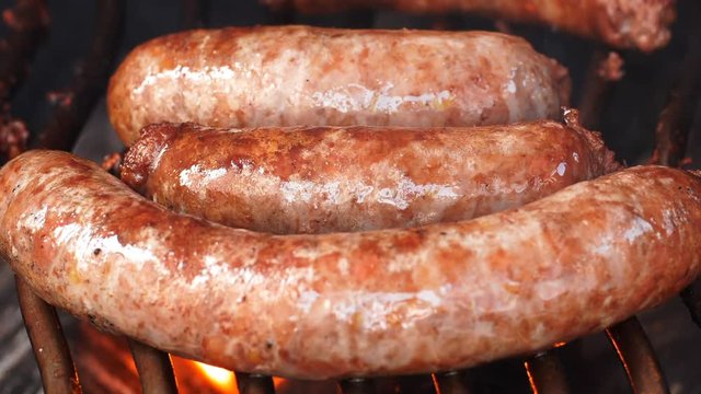 UHD shot of the delicious homemade meat sausages frying on the grill