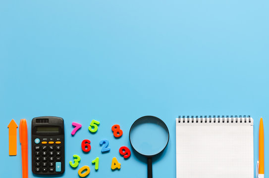 Notebook, calculator, pen, magnifier, colorful numbers on blue background.