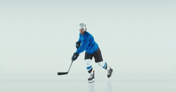 FIXED Portrait of Caucasian male ice hockey player in uniform performing a slap shot against white background. Studio shot. 4K UHD 60 FPS SLOW MOTION