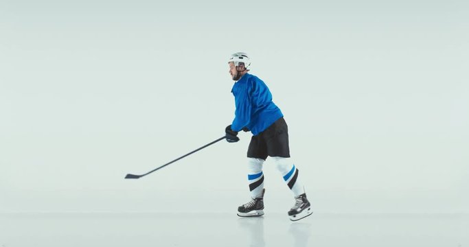 FIXED Portrait of Caucasian male ice hockey player in uniform performing a wrist shot against white background. Studio shot. 4K UHD 60 FPS SLOW MOTION