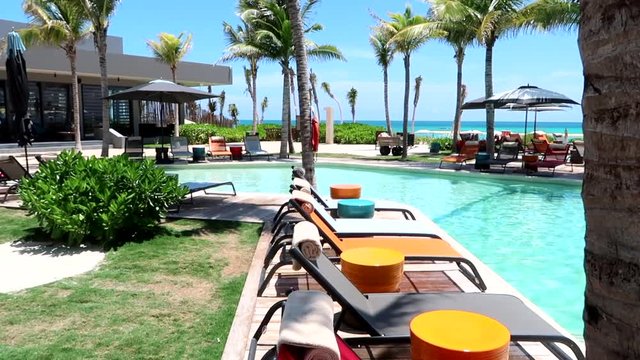 View of lounge chairs, pool, restaurant, and beach at the Andaz Mayakoba Resort in Mexico.