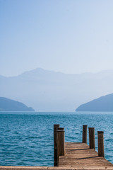 Panorama of mist mountains and Quatre Cantons lake with wood deck foreground, near Lucerne, Switzerland.