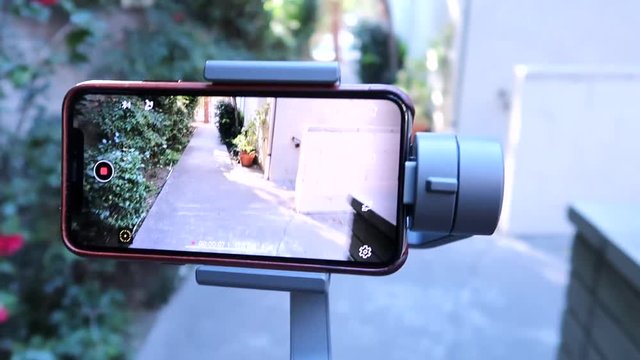 iPhone X being used in a smartphone gimbal while walking.