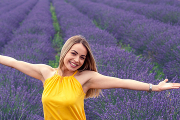 Young smiling woman enjoying in lavender field on summer day.