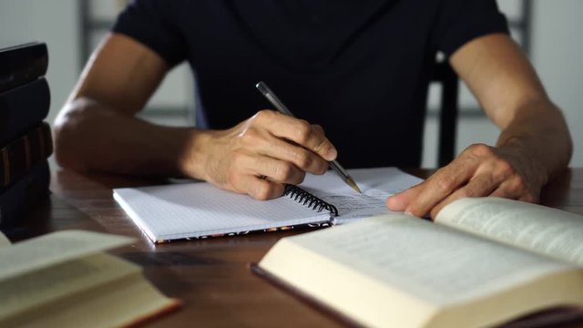 Close-up student's hand writting in a notebook on the table. Studying, university, lessons education concept.