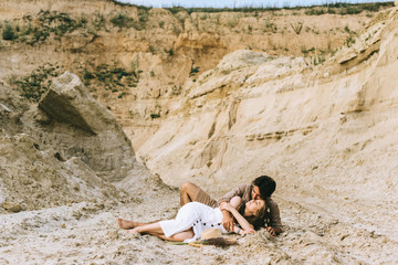 young tender couple hugging and lying in sand canyon