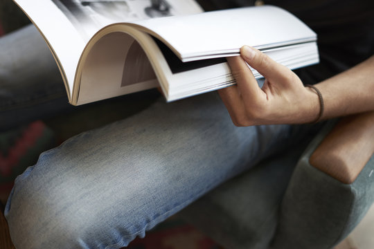 Close-up view of a man hand holding reading modern fashion magazine