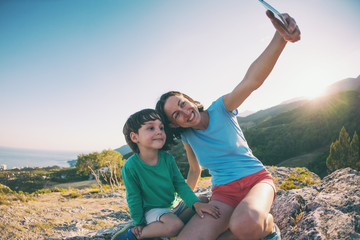 Mother and son make selfie on top of a mountain.
