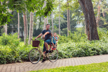 Fototapeta premium Happy family. Smiling father with boy on bicycles having fun in park. Family sport and healthy lifestyle.