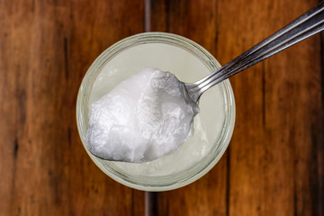 A spoonful of coconut oil set on a wooden background.