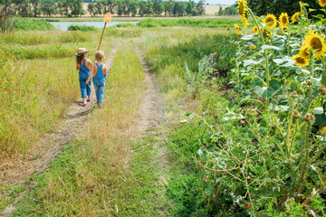 Two children with a butterfly net walk through the countryside
