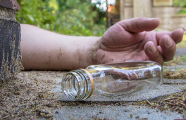 ein schlafender Mann und eine leere Schnapsflasche liegen auf der Strasse

