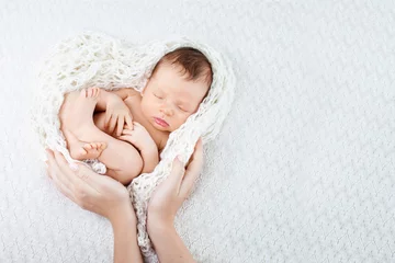 Fototapeten Sleeping newborn baby  in mother hands - hearth shape © fadzeyeva