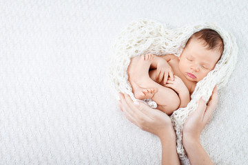 Sleeping newborn baby  in mother hands - hearth shape