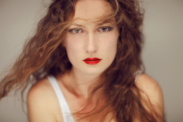 Beautiful young woman with long curly hair and perfect make up beauty portrait, looking into camera