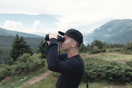 Hiker looking through binoculars in front of hills and mountain range. Prevalla, Prizren, Kosovo
