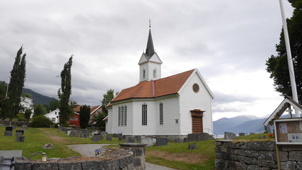 Fototapeta na wymiar Weiße Holzkirche und Friedhof in Tjugum, Norwegen
