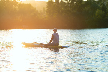 Sup surfer sits on the sup board in the golden light