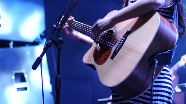 Singer girl during a concert playing an acoustic guitar