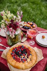 berries pie and bouquet of flowers on table in garden