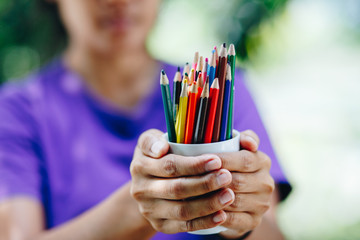 Stack of colored pencils in woman hands, art design concept