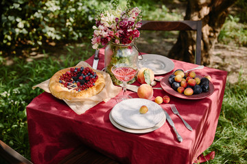 wineglass, berries pie and fruits on table in garden