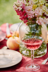 wineglass and bouquet of flowers on table in garden