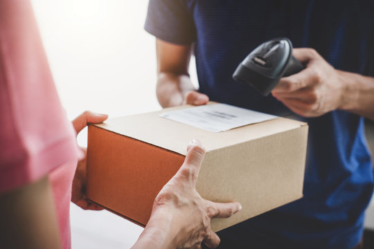 Home delivery service and working service mind, Woman customer hand receiving a cardboard boxes parcel from service courier and deliveryman scan barcode to confirm delivery