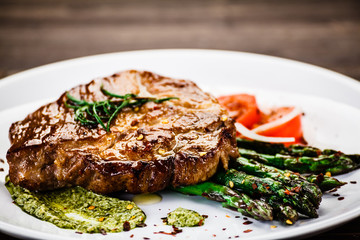 Grilled beefsteak with asparagus on wooden background 