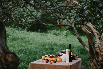 candles, glasses with wine and pie on table in garden