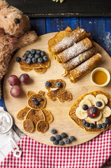 Children's breakfast. Pancakes with berries and warriors, with cheerful faces. Top view