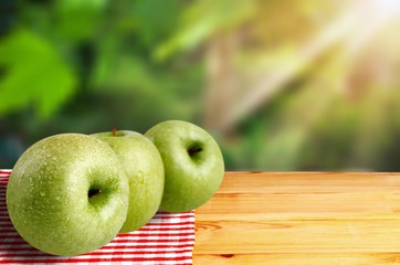 Row of green apples on desk