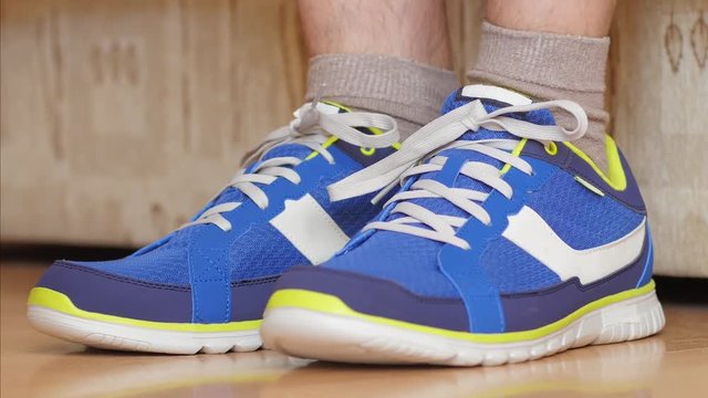 Man is going to do sports work out - tying the laces on sneakers