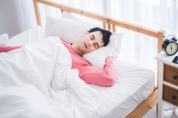 Fototapeta na wymiar sleepy man on the bed with alarm clock in the morning