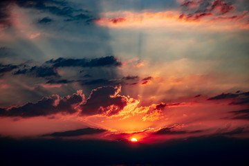 Brilliant sunset with rays of light shining behind the clouds