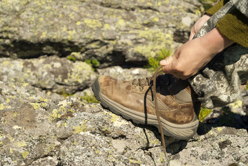 hands tying shoelaces on a worn hiking boot close-up
