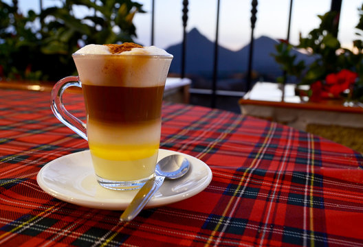 Traditional Canarian coffee Barraquito with separated layers of milk condensed and liquor on the terrace of cafe in Tenerife,Canary Islands,Spain.Selective focus.