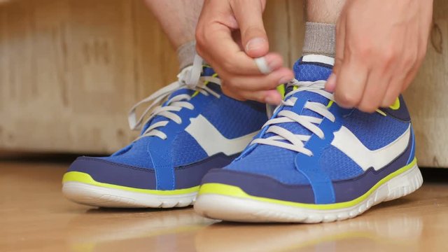 Man is going to do sports work out - tying the laces on sneakers